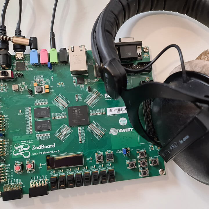 FPGA development board next to a pair of headphones